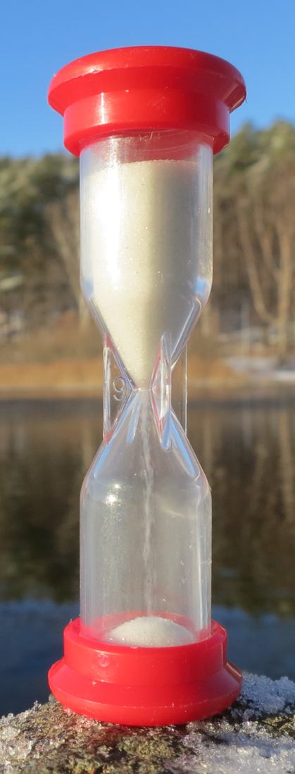 Hourglass on a lakeside railing
