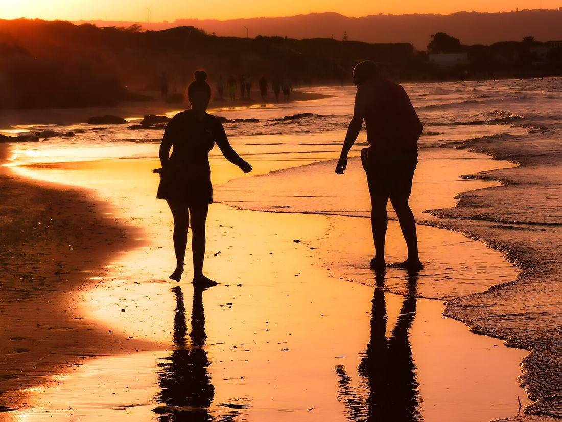 Couple silhouetted on a beach at sunset