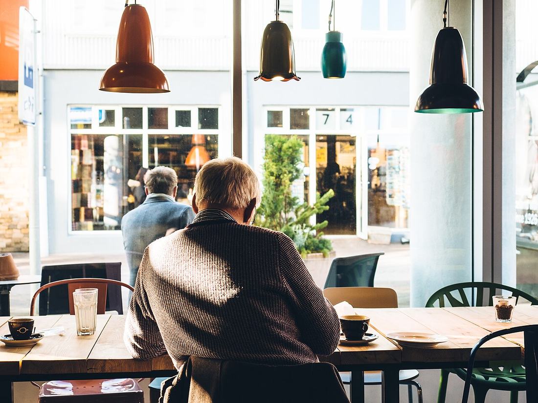 Older man reading a newspaper in a café