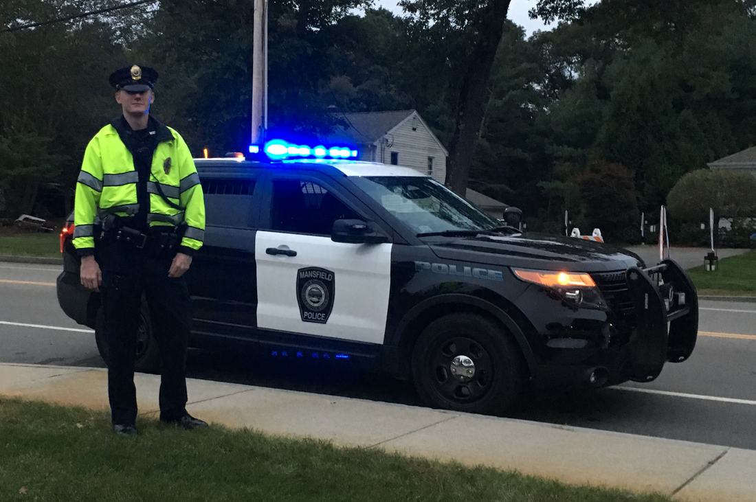 Police officer standing by a patrol car